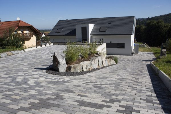 Einfahrt mit Pflastersteinen und einem Familienhaus.